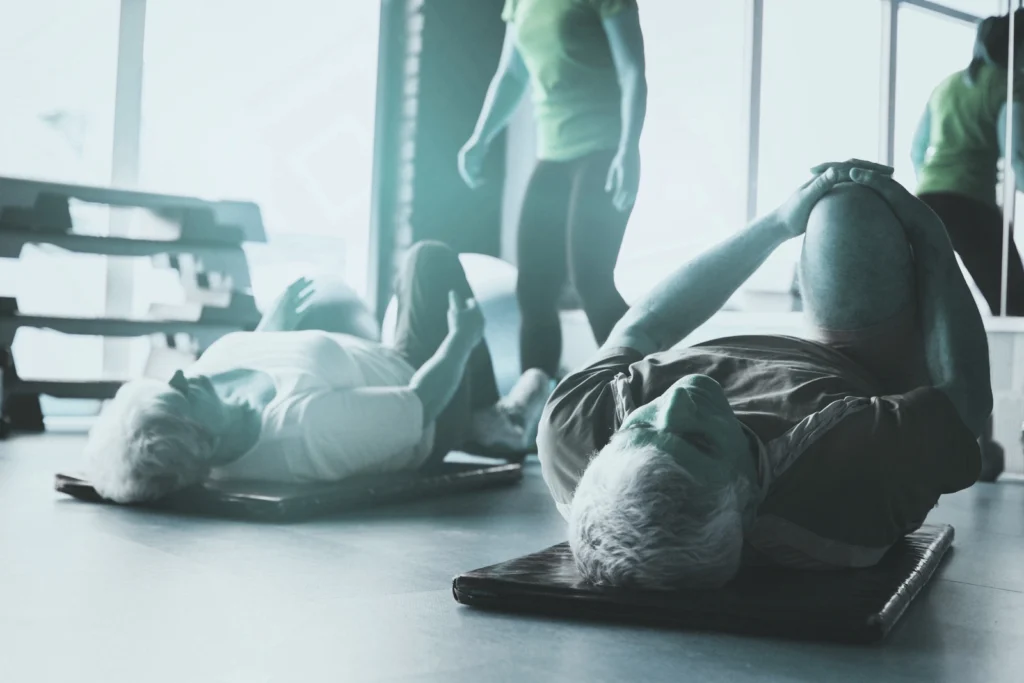 Kobieta i mężczyzna wykonują pozycje leżące jogi pod okiem instruktorki