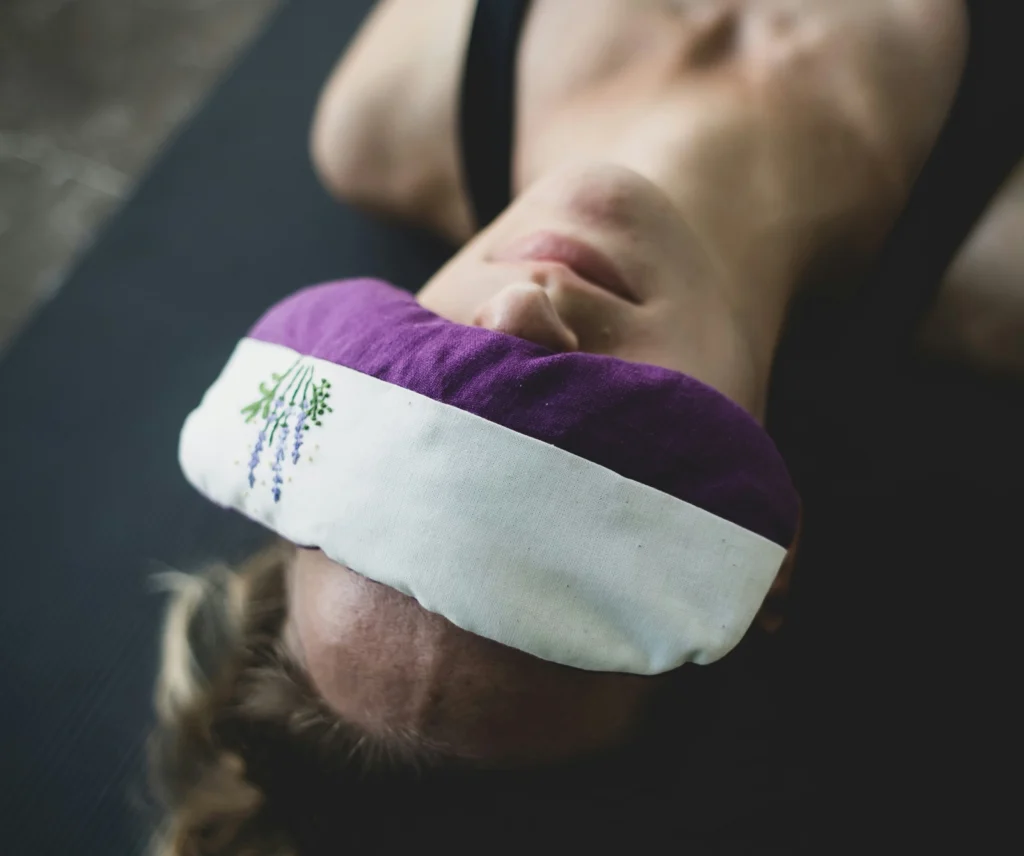 Kobieta leży na macie z woreczkiem na oczach